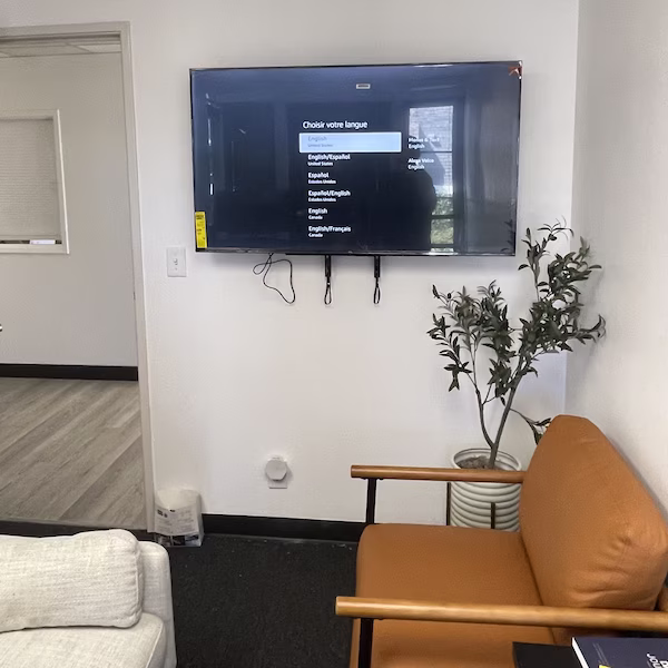 Mounted flat-screen TV in lounge with wires ready for management. Clean, secure wall mount by our Orange County handyman services team.