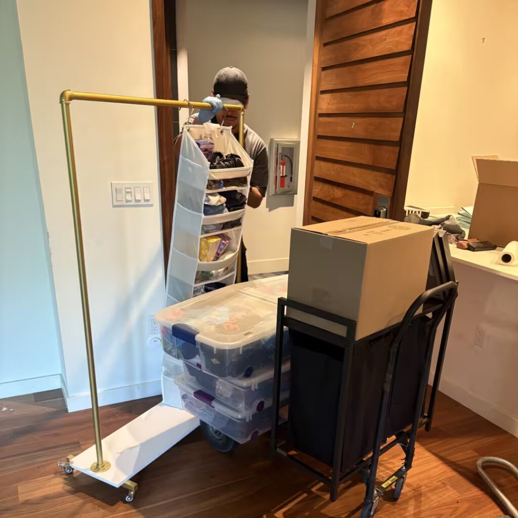 OC Bros mover organizing apartment items with boxes and bins on carts during a local Orange County move.